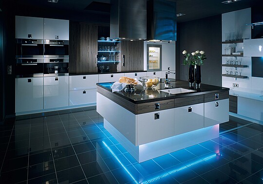 Blau beleuchtete Kücheninsel in einer weißen Küche
